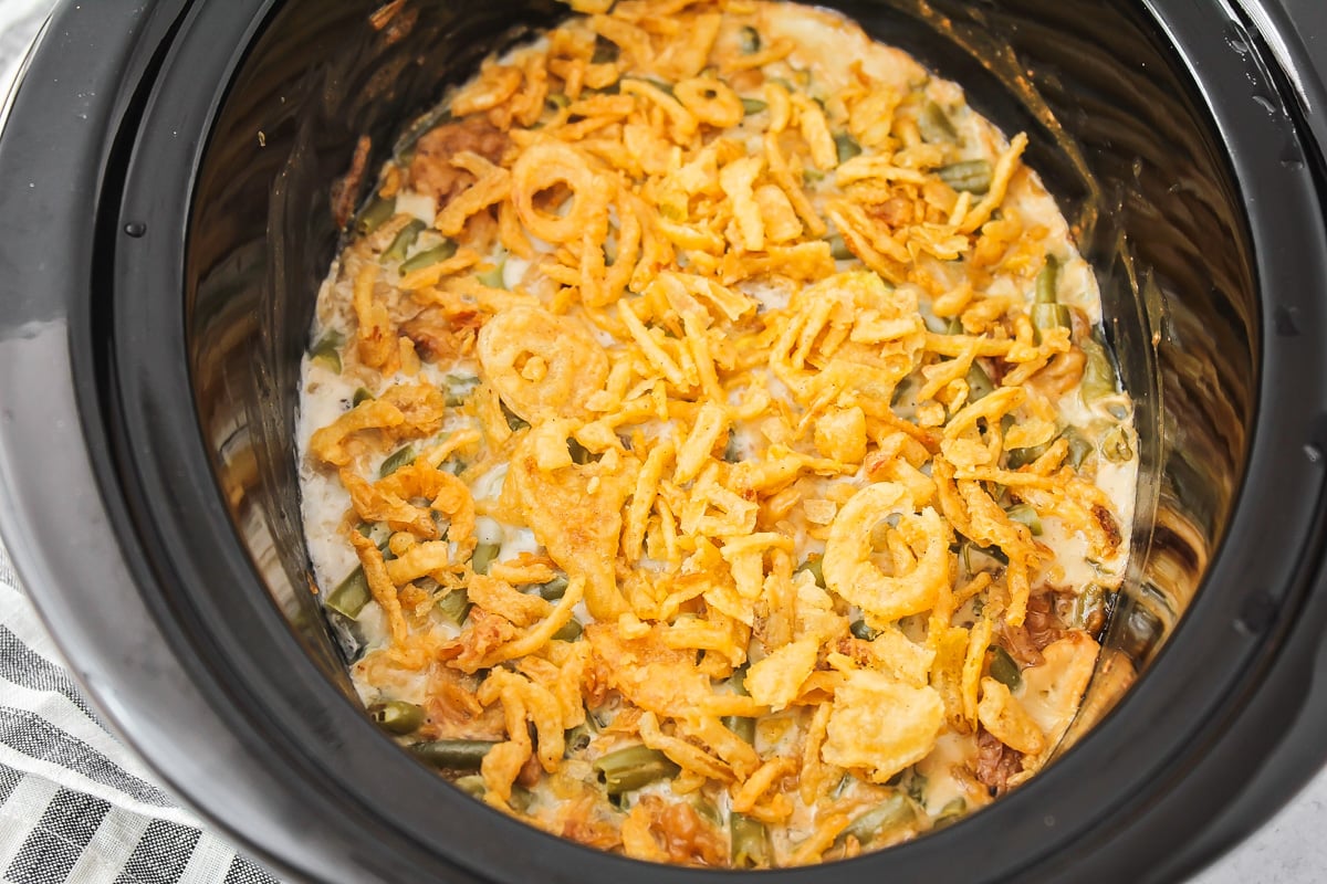Green bean mixture topped with crispy onions in a slow cooker.