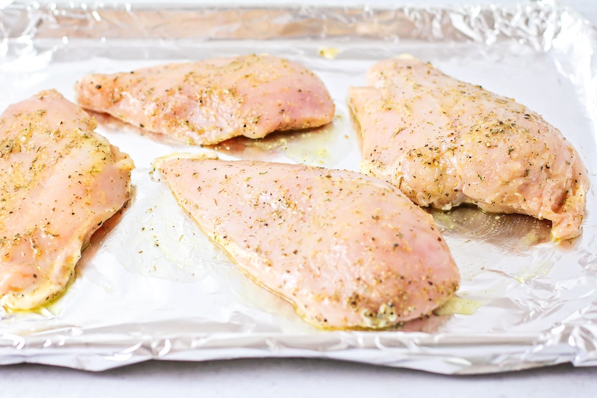 Seasoned chicken on a pan for making baked chicken.