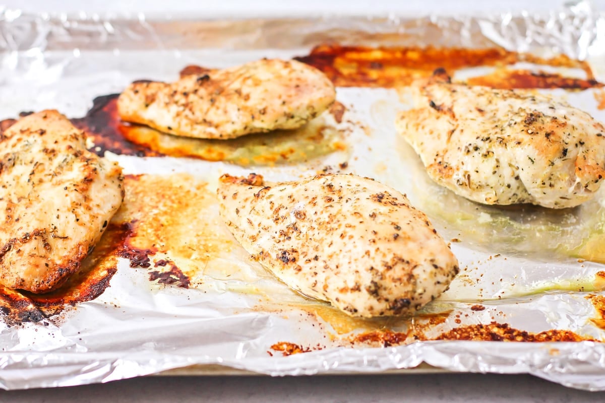 Oven baked chicken breasts on a baking sheet straight from the oven.