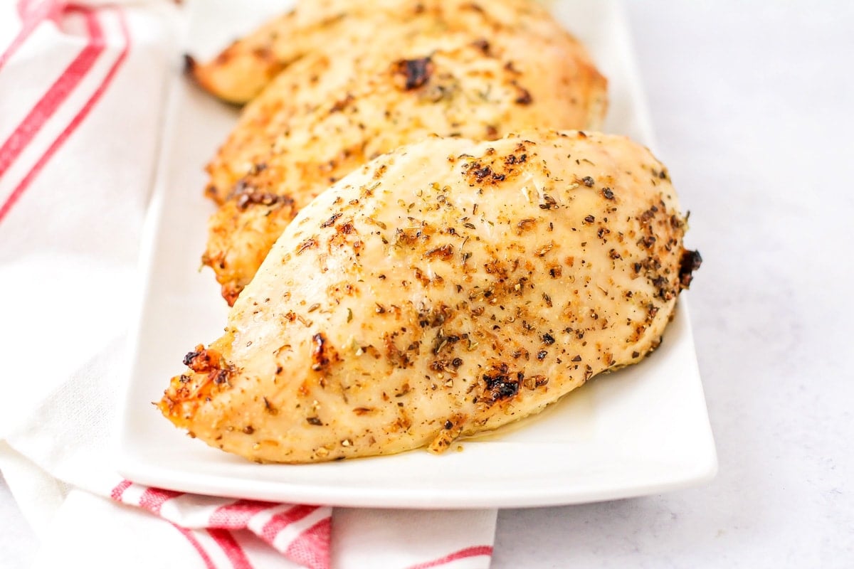 Oven baked chicken breasts on a white platter.