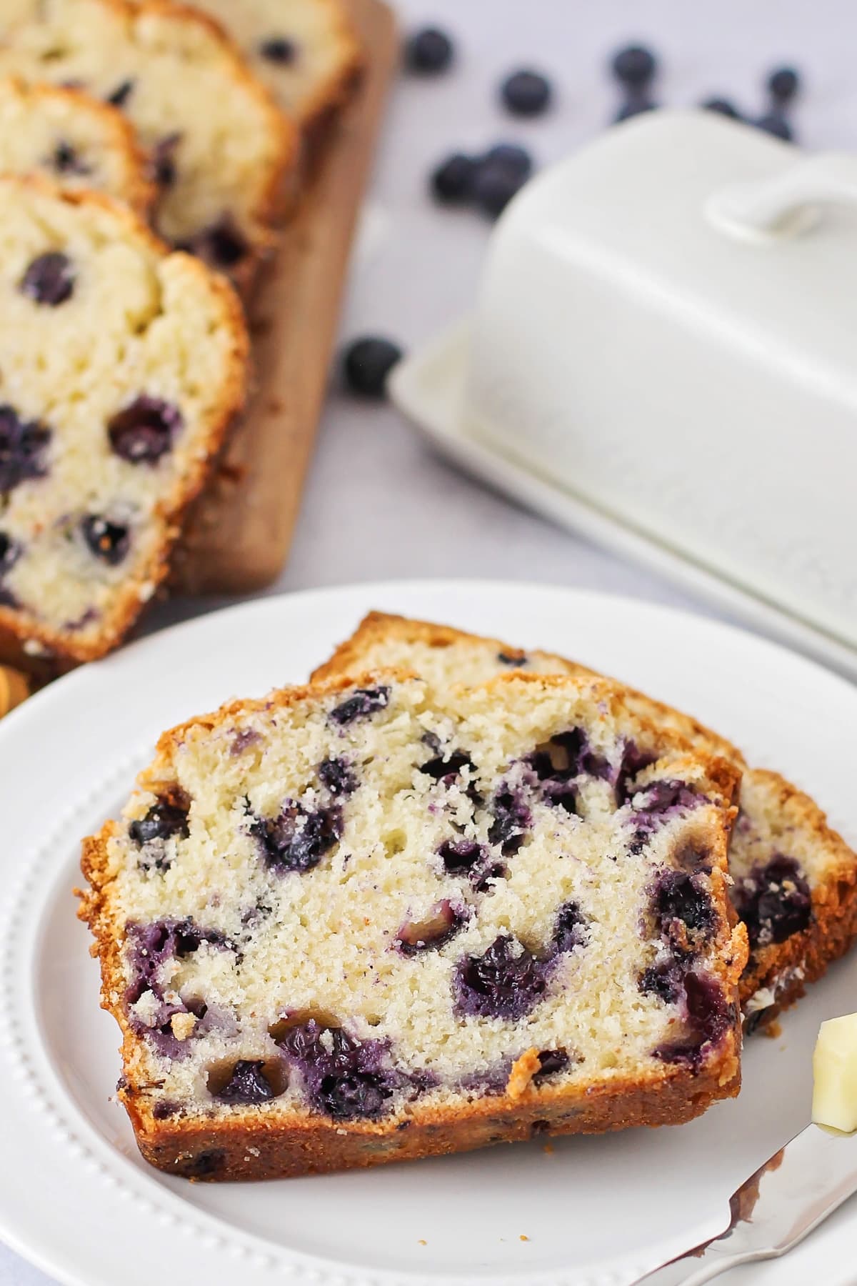 Close up of two slices of blueberry bread on a white plate.