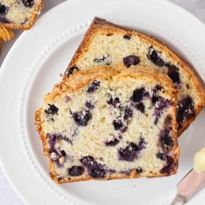 Two slices of blueberry bread served on a white plate.