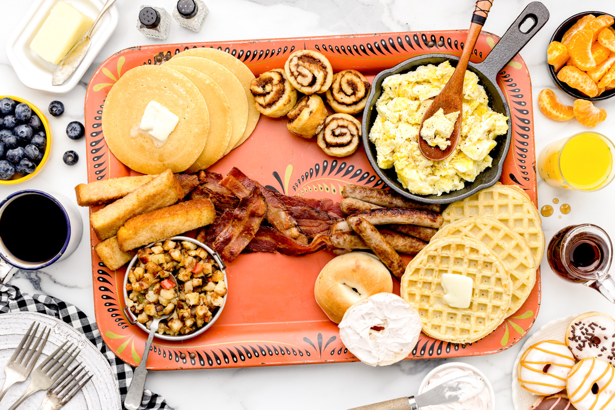 Placing bacon and sausage onto a breakfast charcuterie board.