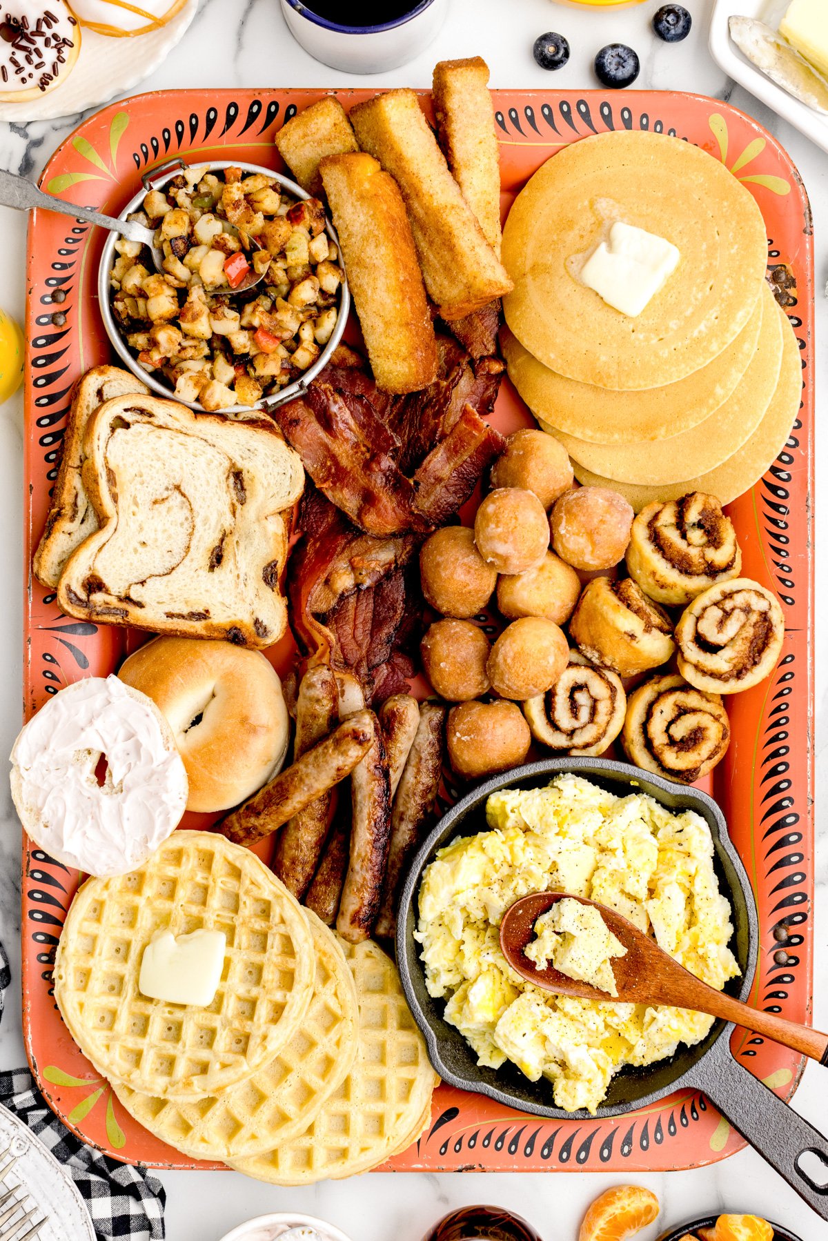 A breakfast charcuterie board filled with eggs, meat, and baked breakfast items.