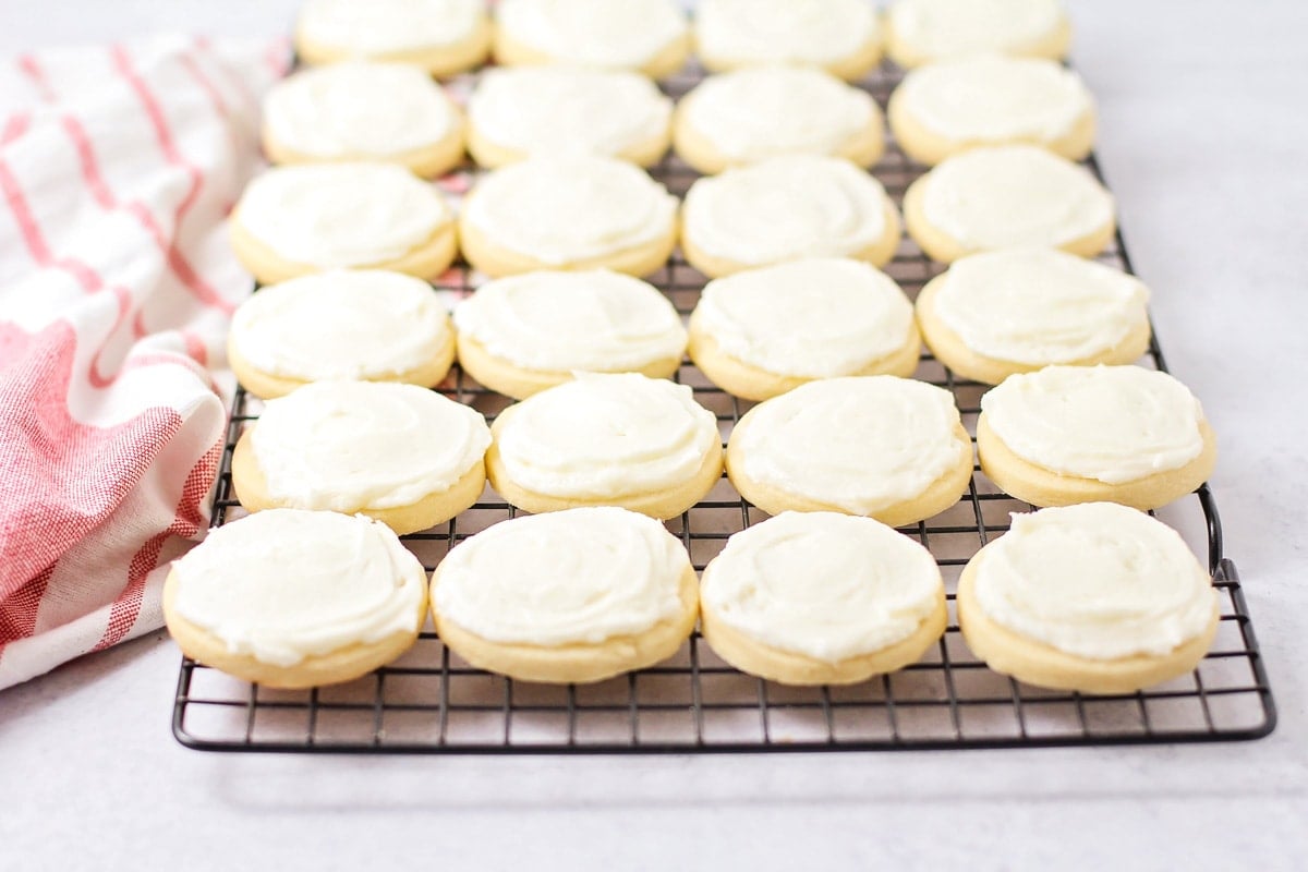 Several frosted butter cookies cooling on a wire rack.