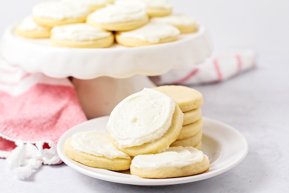 Frosted and stacked butter cookies on a white plate.