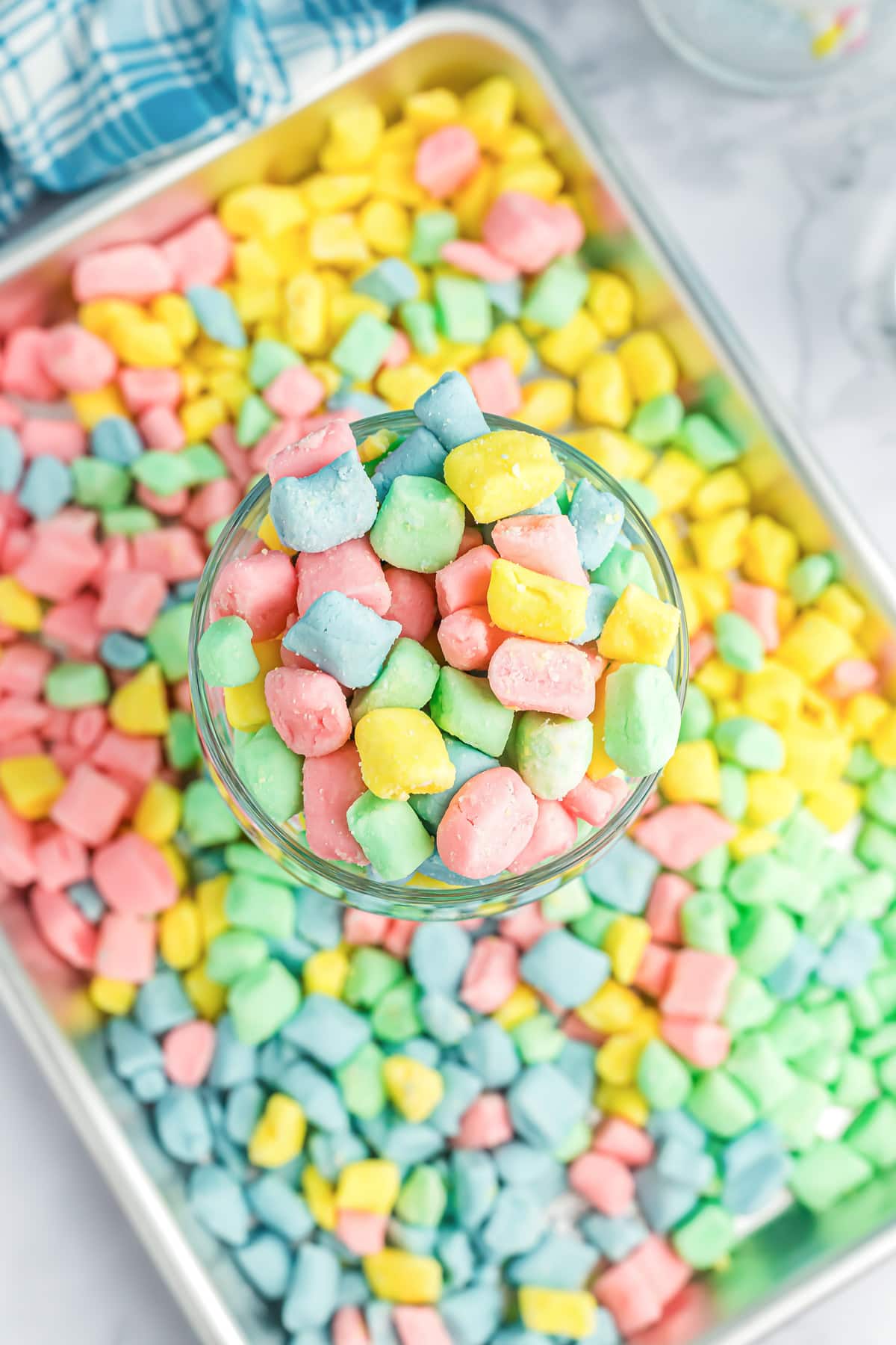 A close up of a cup and tray filled with different colored butter mints.