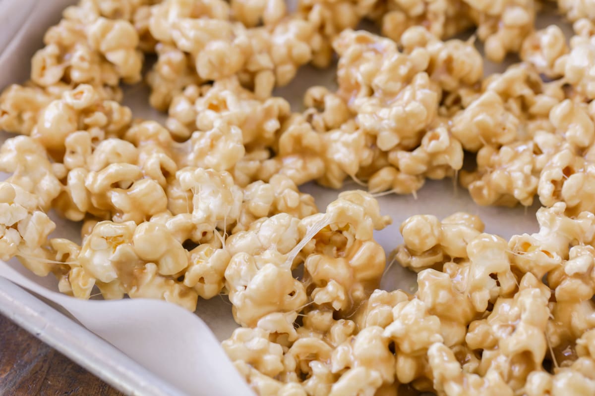 Gooey Caramel marshmallow popcorn on baking sheet lined with parchment paper.