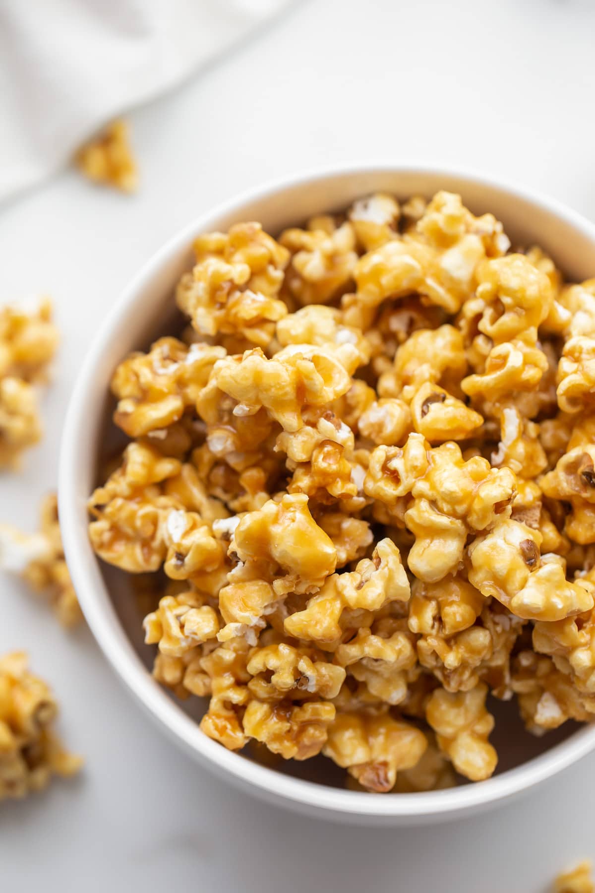 Close up of a white bowl filled with caramel popcorn.