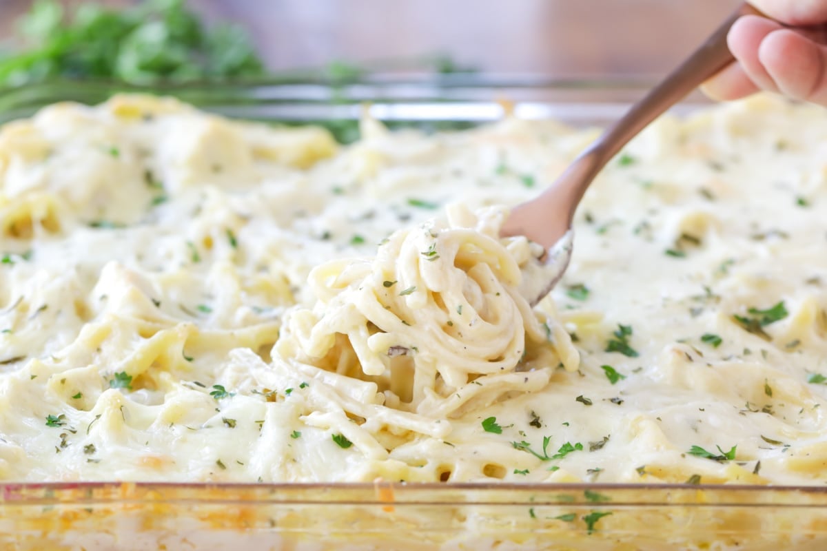 Valentines Dinner Ideas - Chicken Tetrazzini with a metal fork in it in a clear baking dish. 