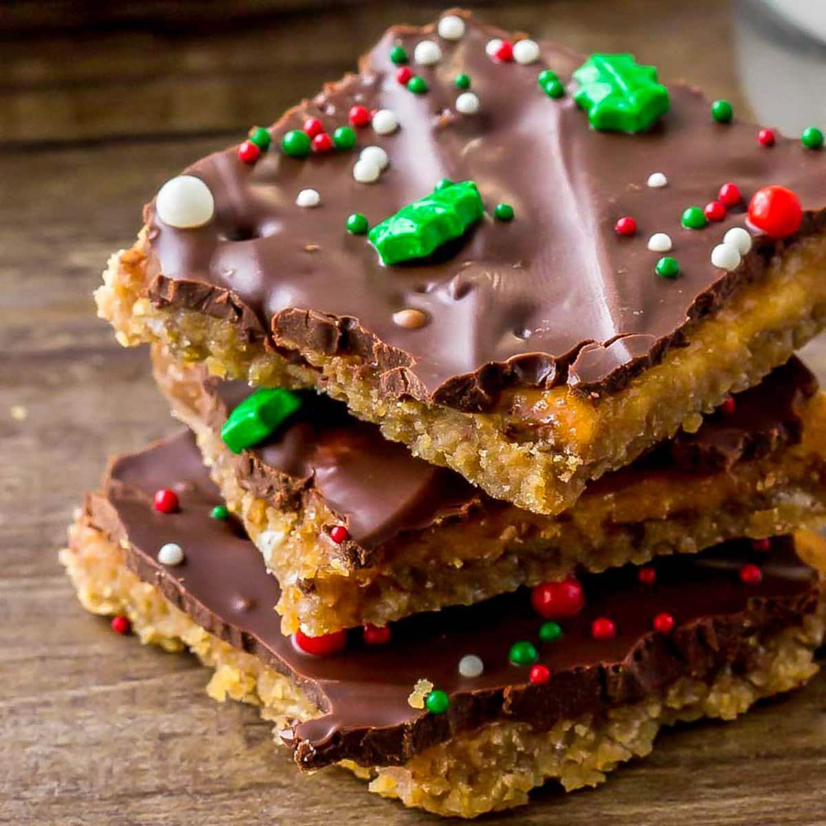 Close up of Christmas crack recipe stacked and topped with sprinkles.