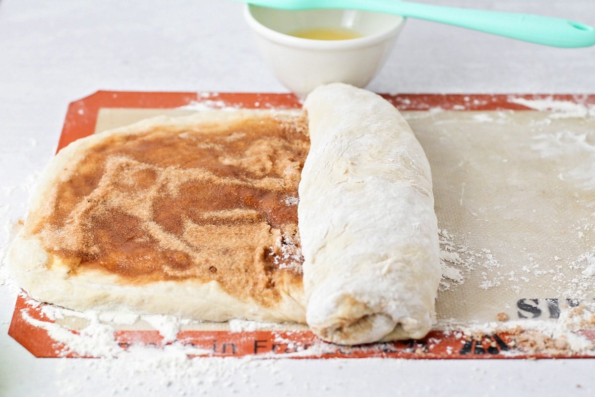 Rolling cinnamon bread dough into a loaf.