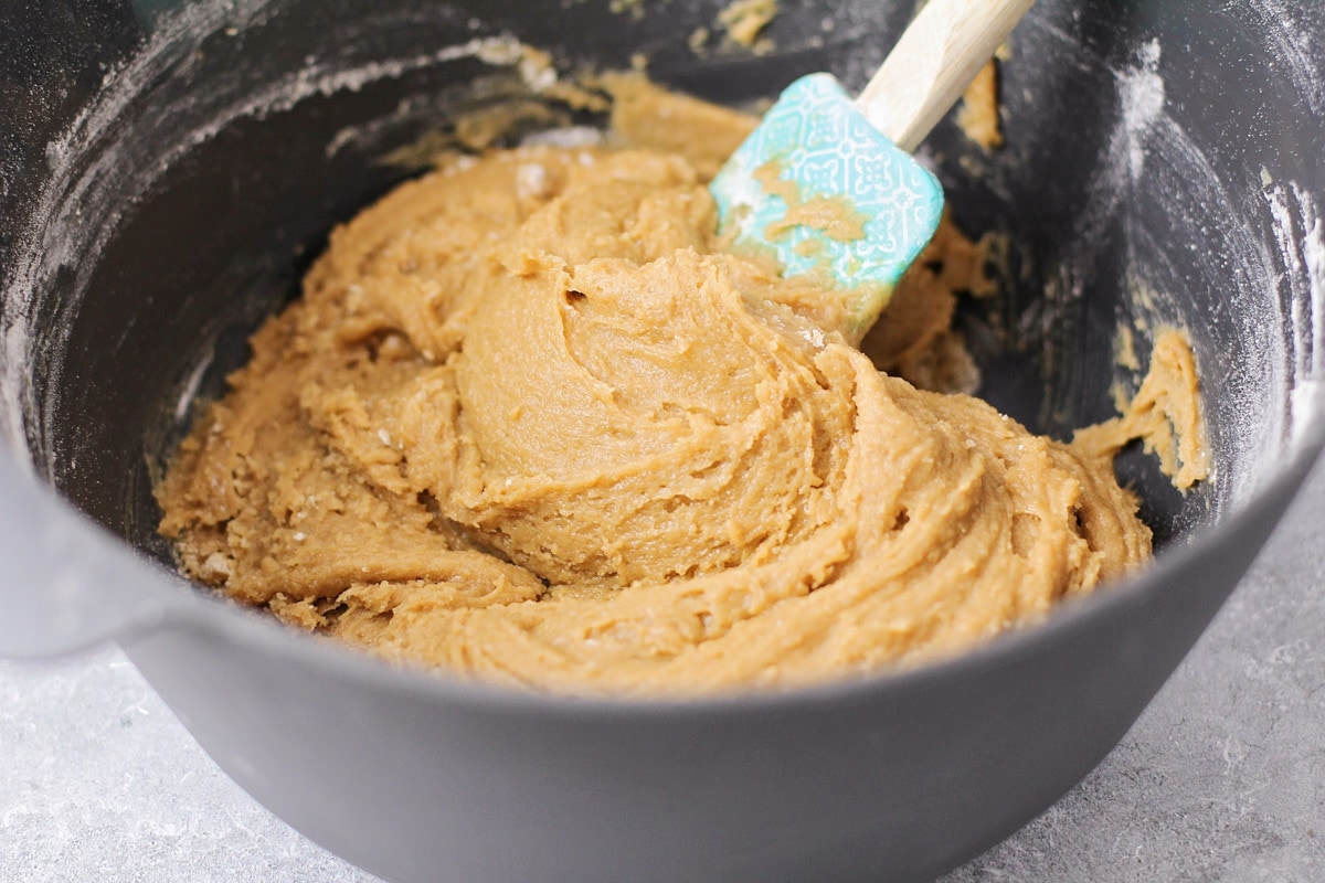 Stirring dough for cookie bars with a rubber spatula in a bowl.