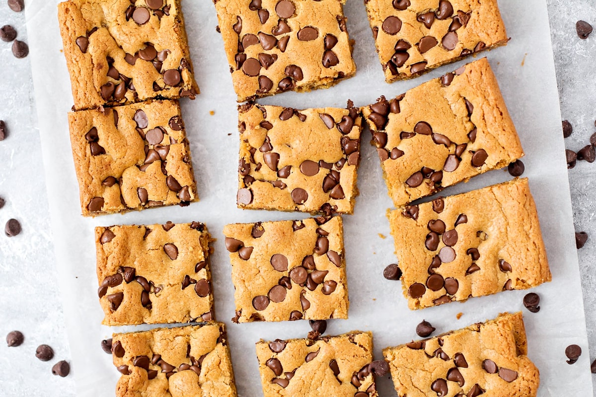 Chocolate chip cookie bars cut on parchment paper.