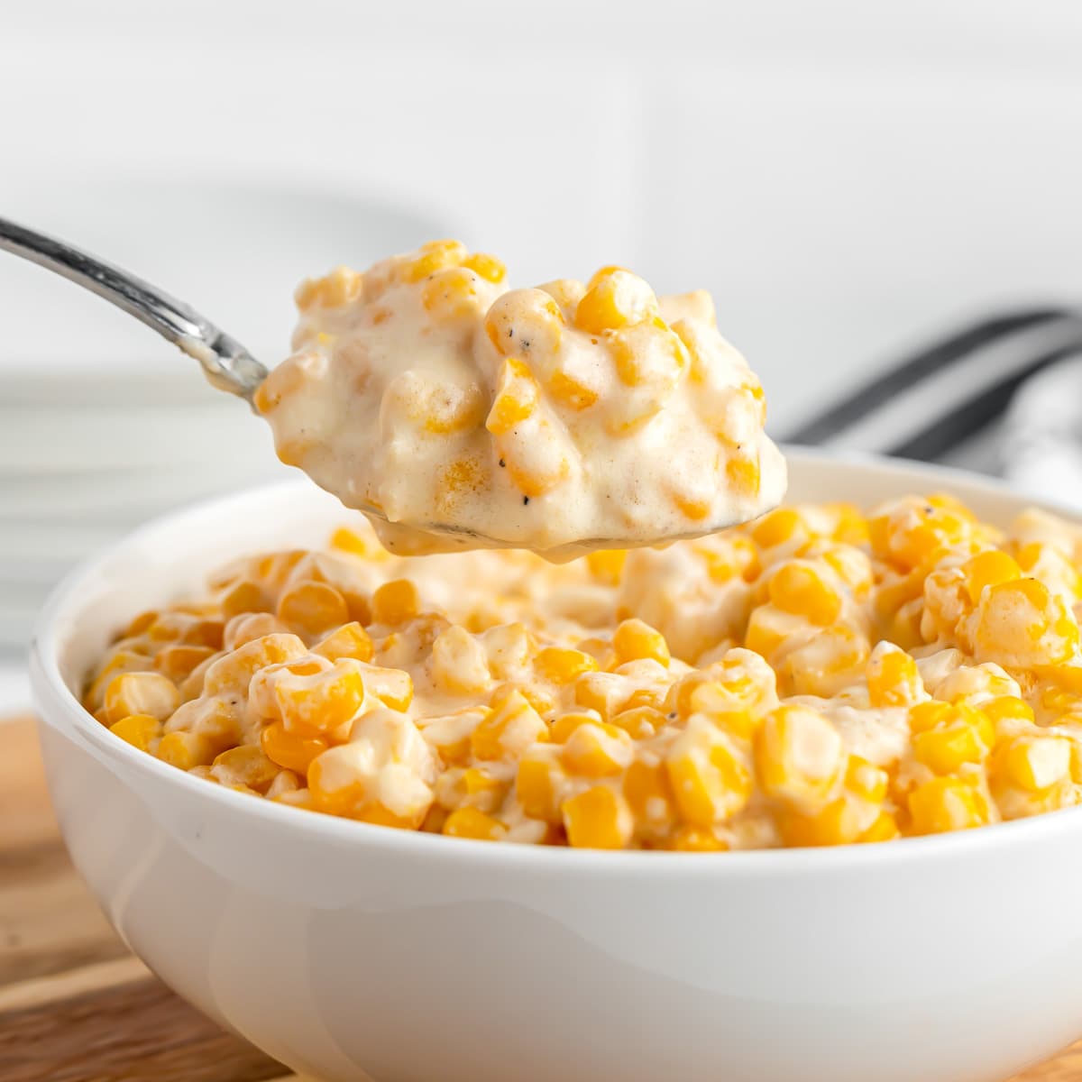 A spoon full of slow cooker creamed corn from a bowl.