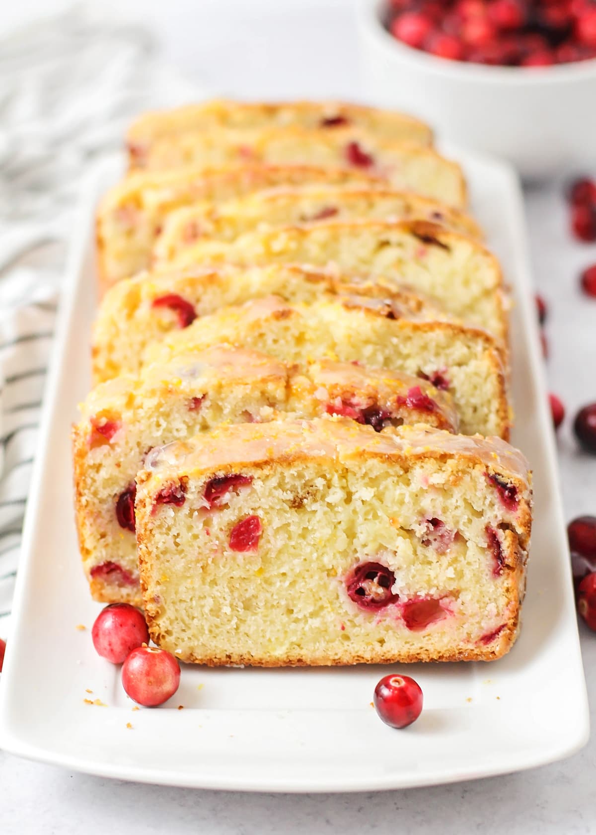 Close up of sliced orange cranberry bread on a white plate.