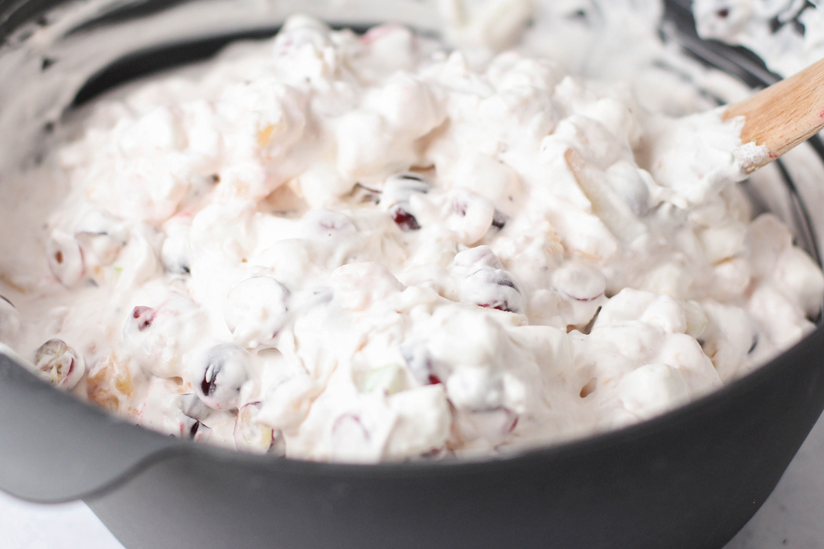 Combining the fruit and whipped cream for making easy cranberry salad.