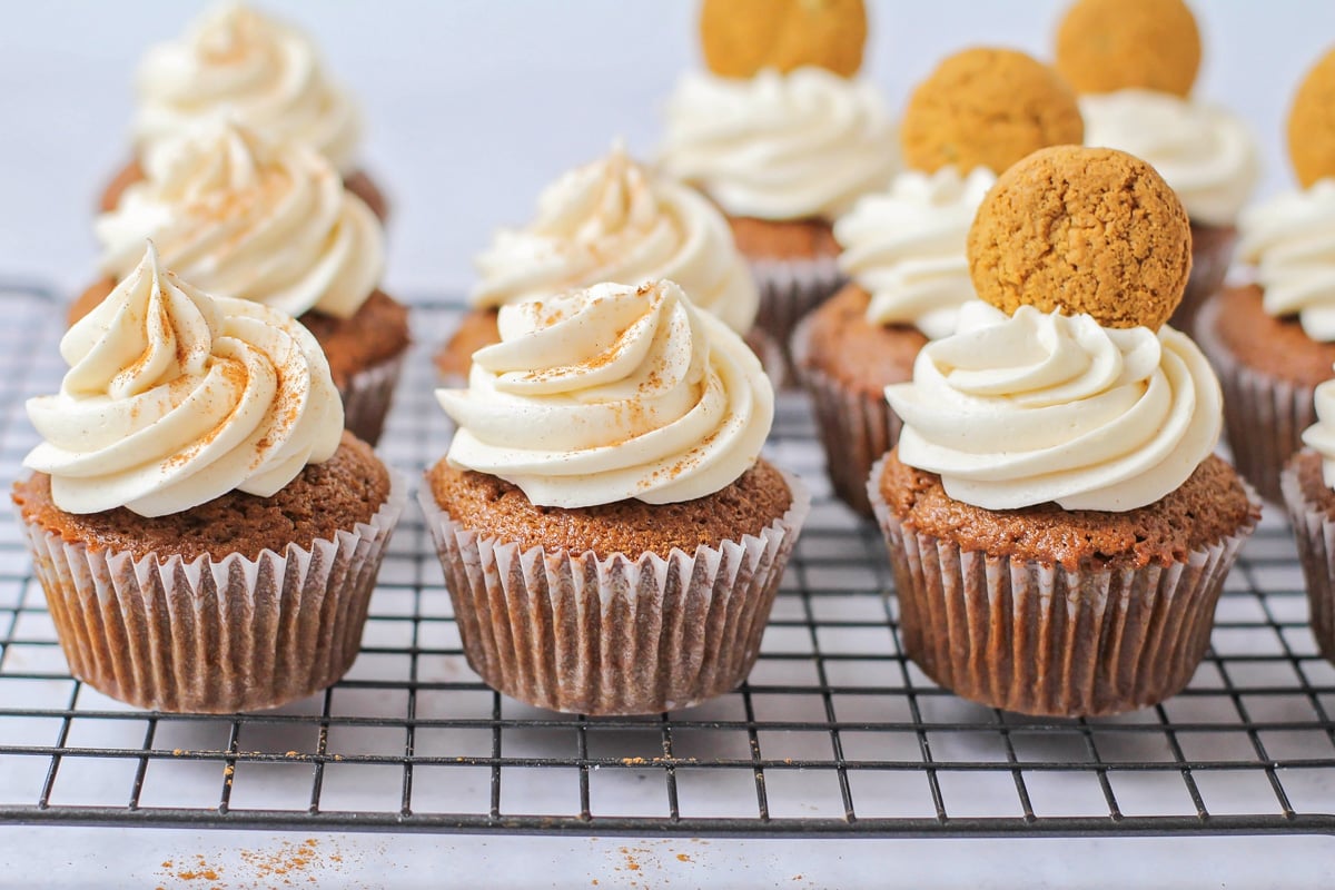 Cinnamon cream cheese frosted gingerbread cupcakes topped with a gingerbread cookie.