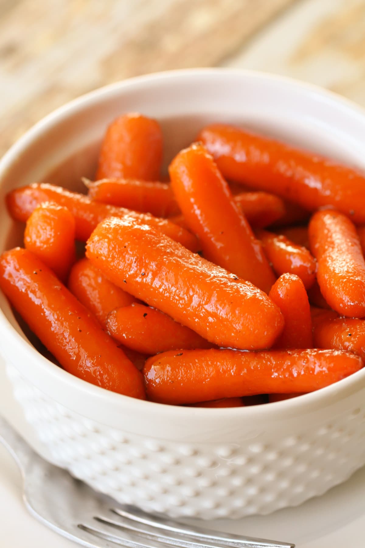 Brown sugar glazed Candied Carrots served in a white bowl.