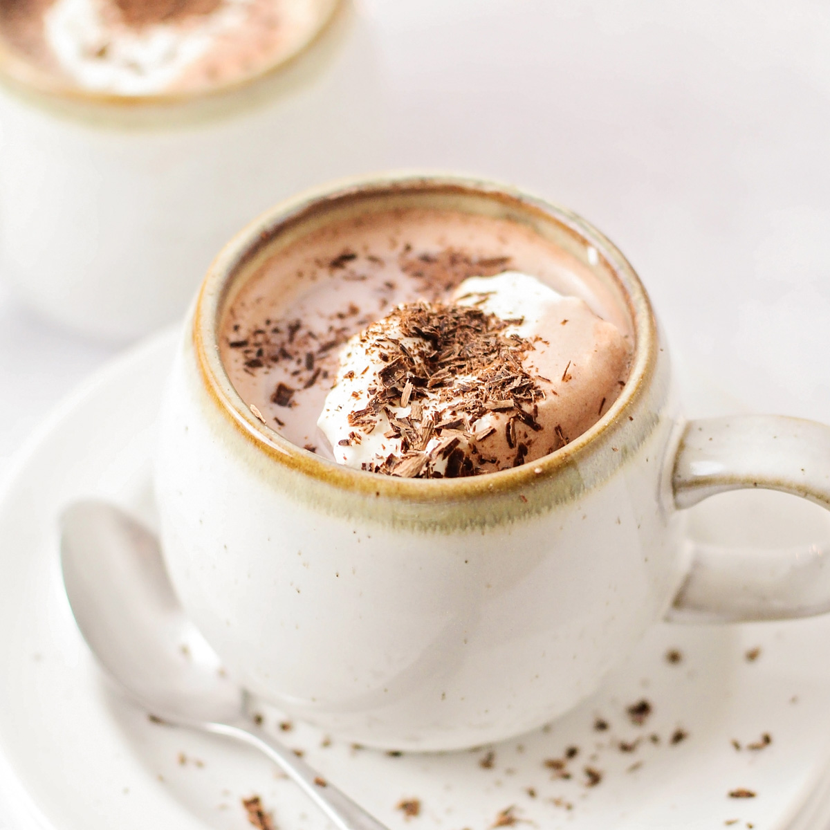 Close up of a mug filled with homemade hot chocolate recipe topped with whipped cream.