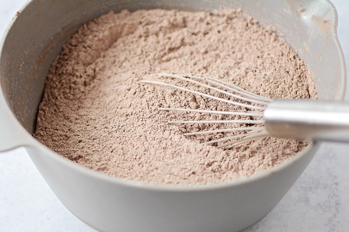 Cocoa powder, flour, and sugar mixed in a grey bowl.