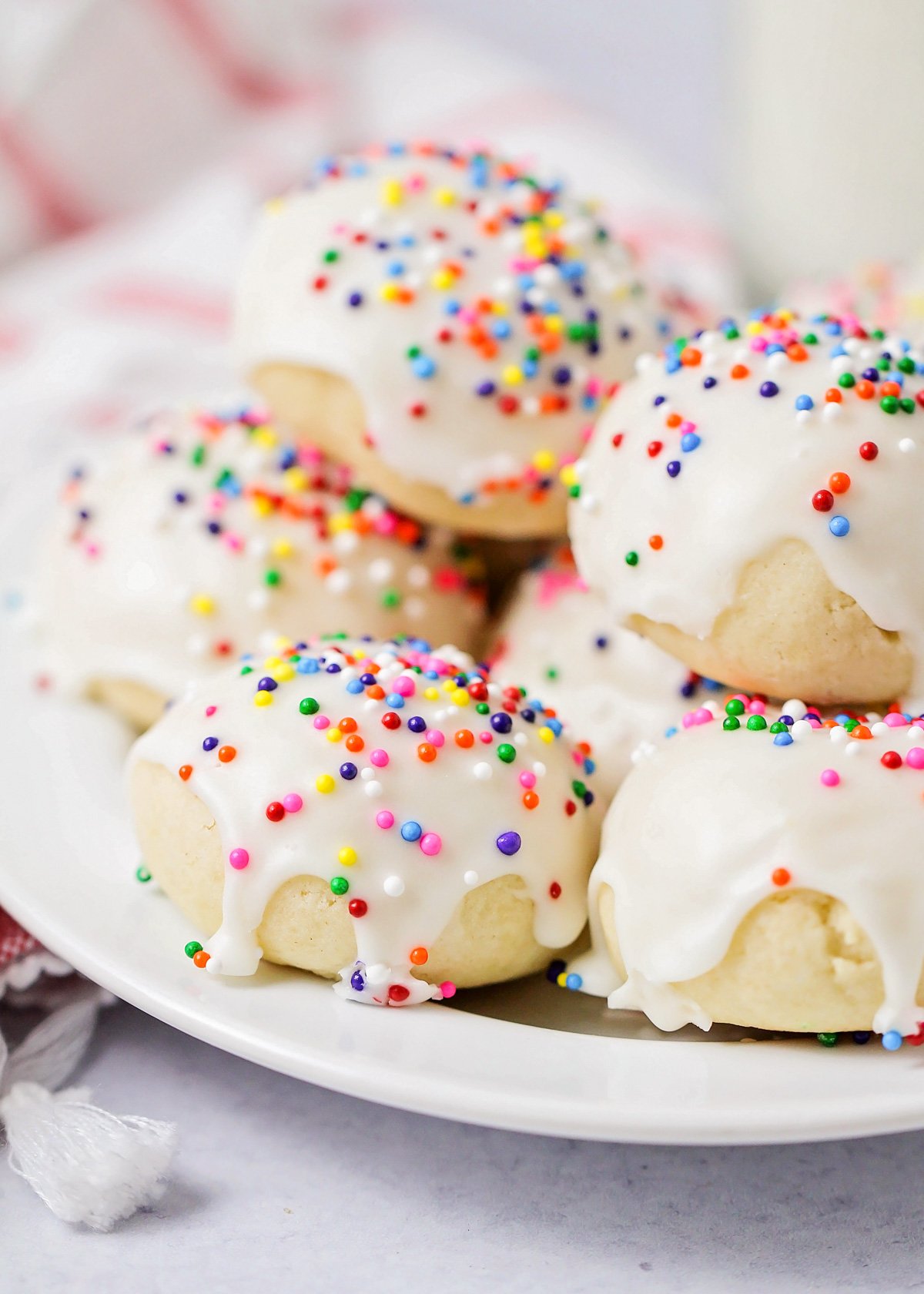 A close up of glazed Italian cookies topped with sprinkles.