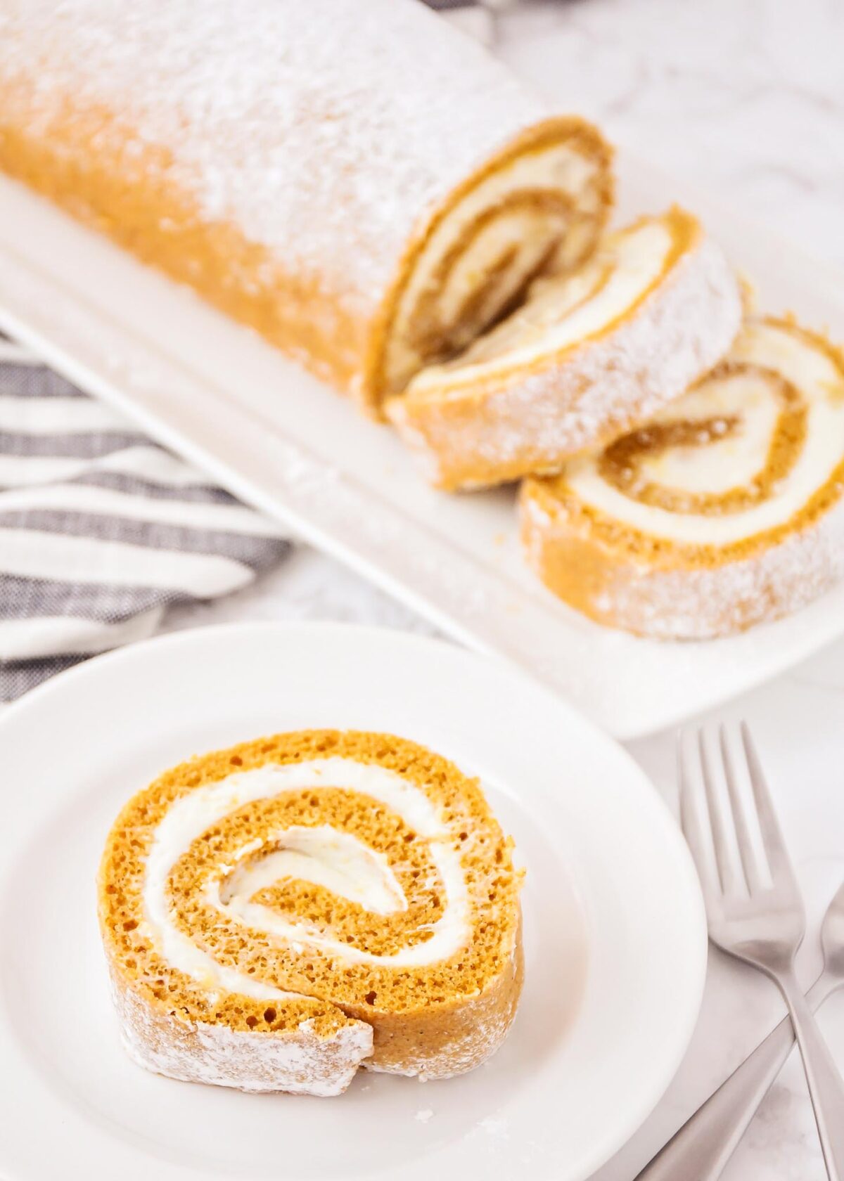 Pumpkin Roll with cream cheese filling sliced and served on a white plate.
