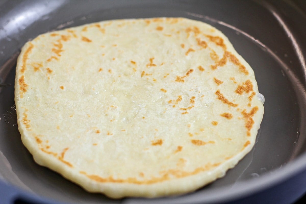 Homemade naan recipe cooking on stove.