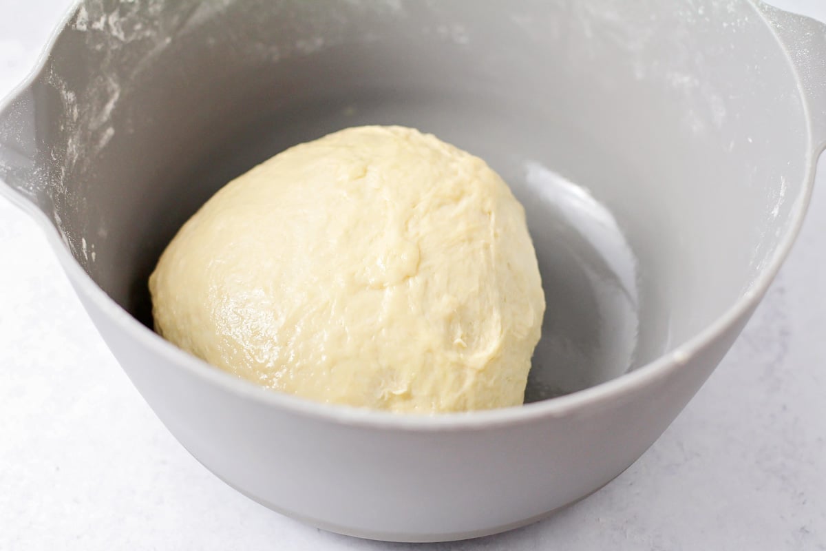 Naan dough rolled in ball in bowl.