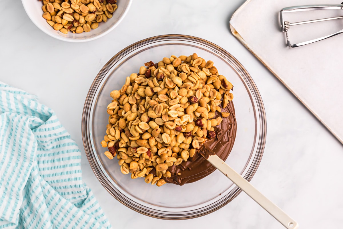 Combining peanuts and chocolate for making peanut clusters.