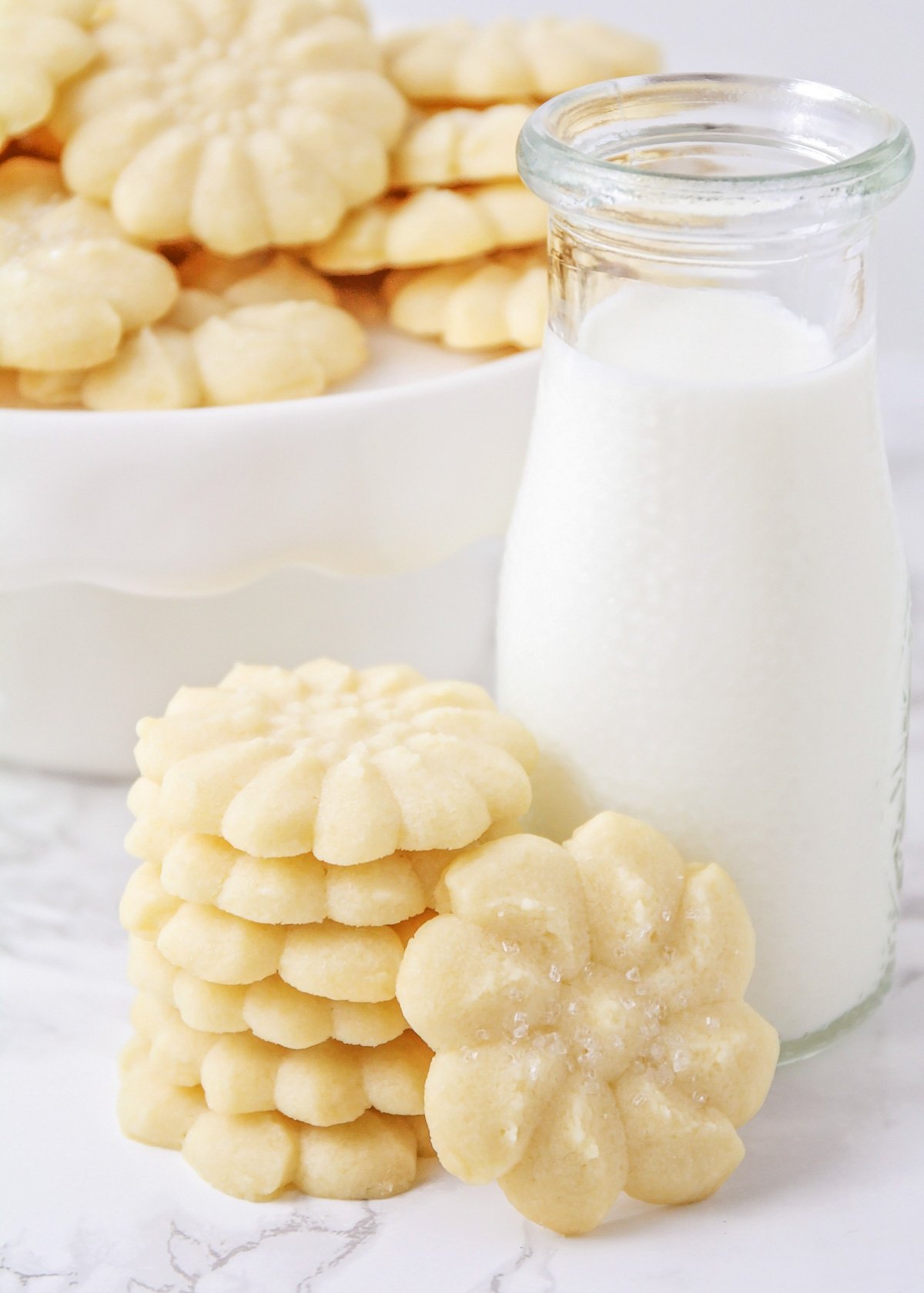 A stack of classic shortbread cookies next to a glass of milk.