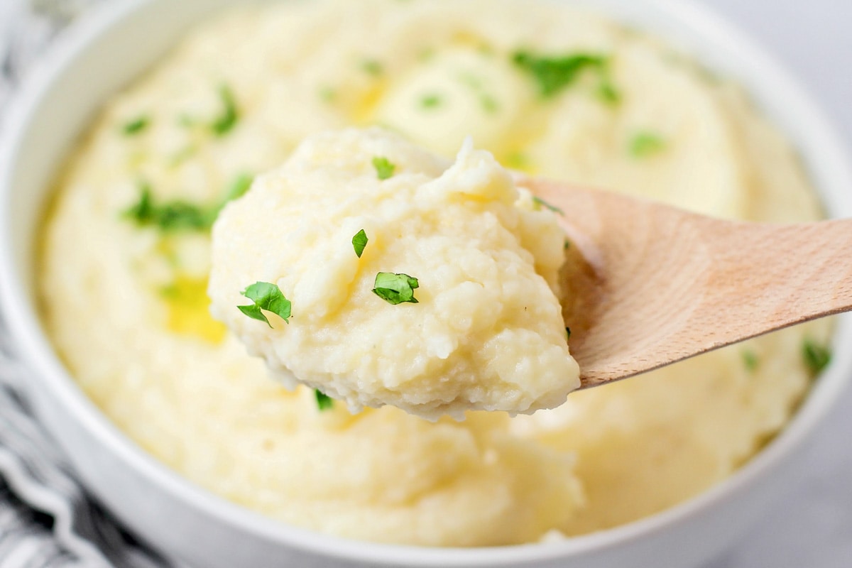 Creamy mashed potatoes made in crock pot on spoon.