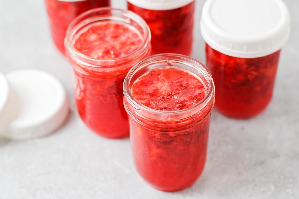 Strawberry jam in mason jars cooling on the counter.