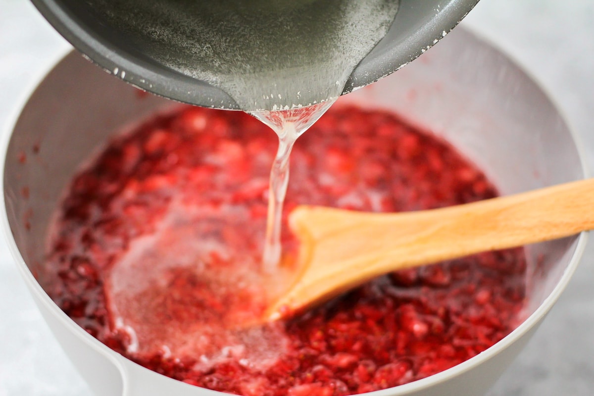 Adding pectin mixture to strawberry jam.