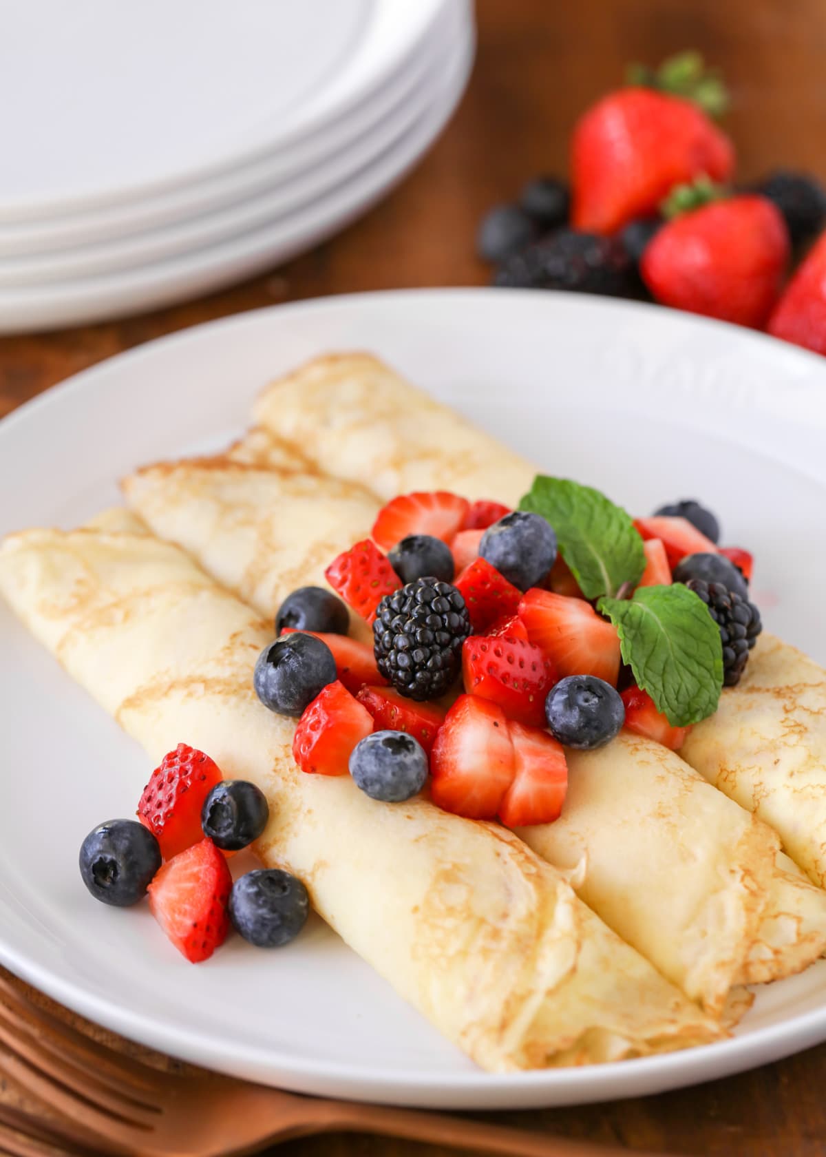 Three swedish pancakes topped with fresh mint and berries.