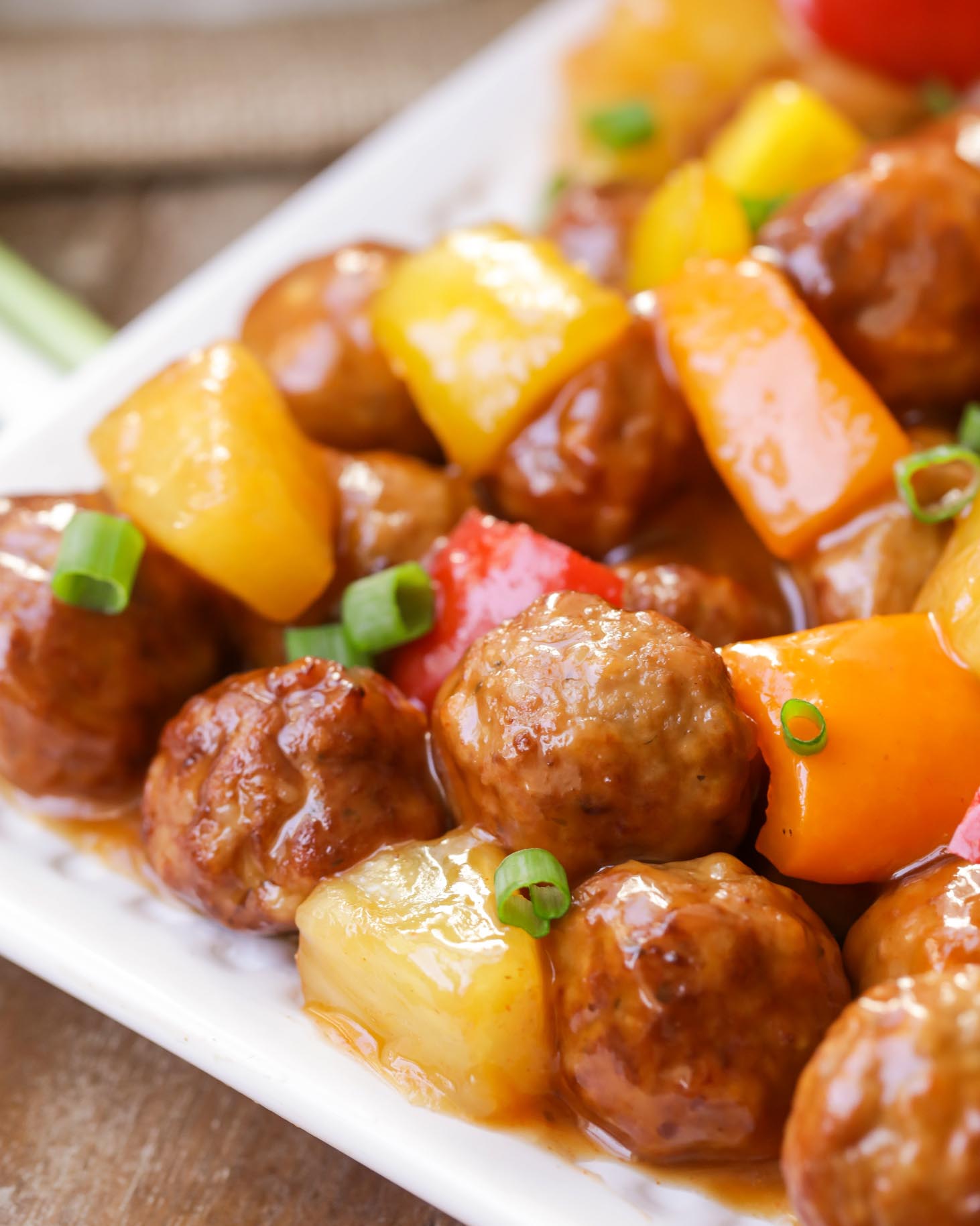 Close up of sweet and sour meatballs topped with green onions.