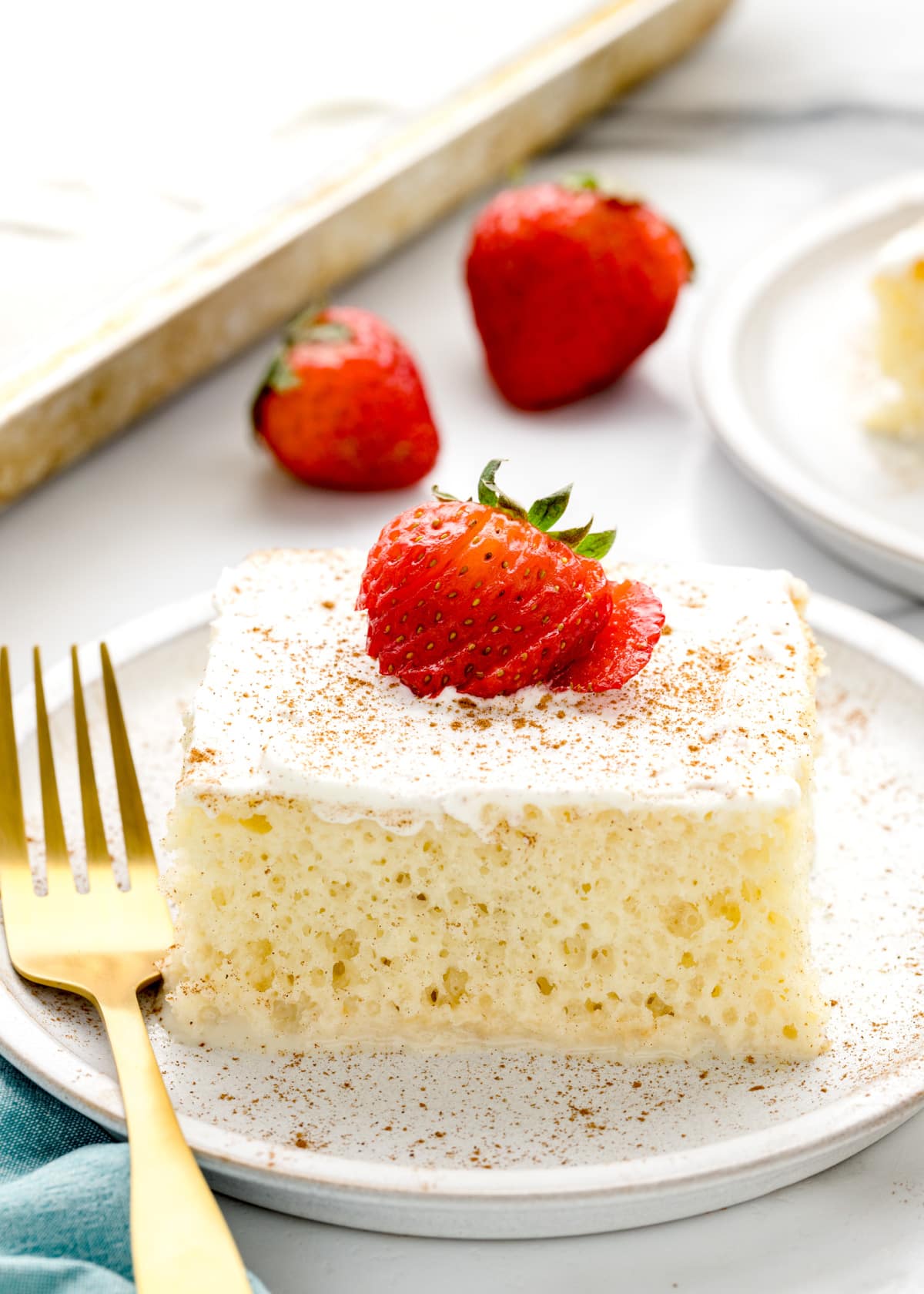 A close up of a slice of tres leches cake with cake mix topped with a fresh strawberry.
