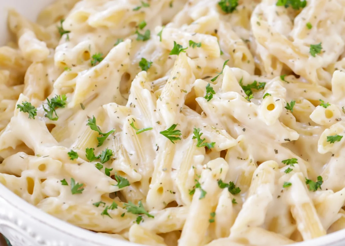 Close up image of penne pasta covered in white sauce.