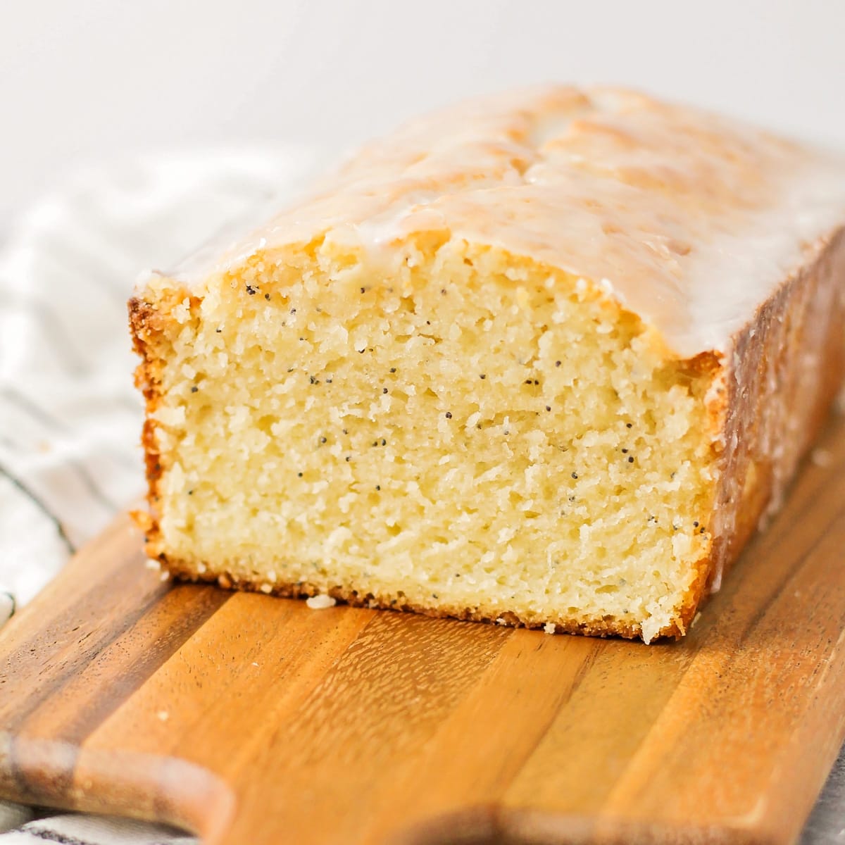 A loaf of almond poppy seed bread topped with glaze.