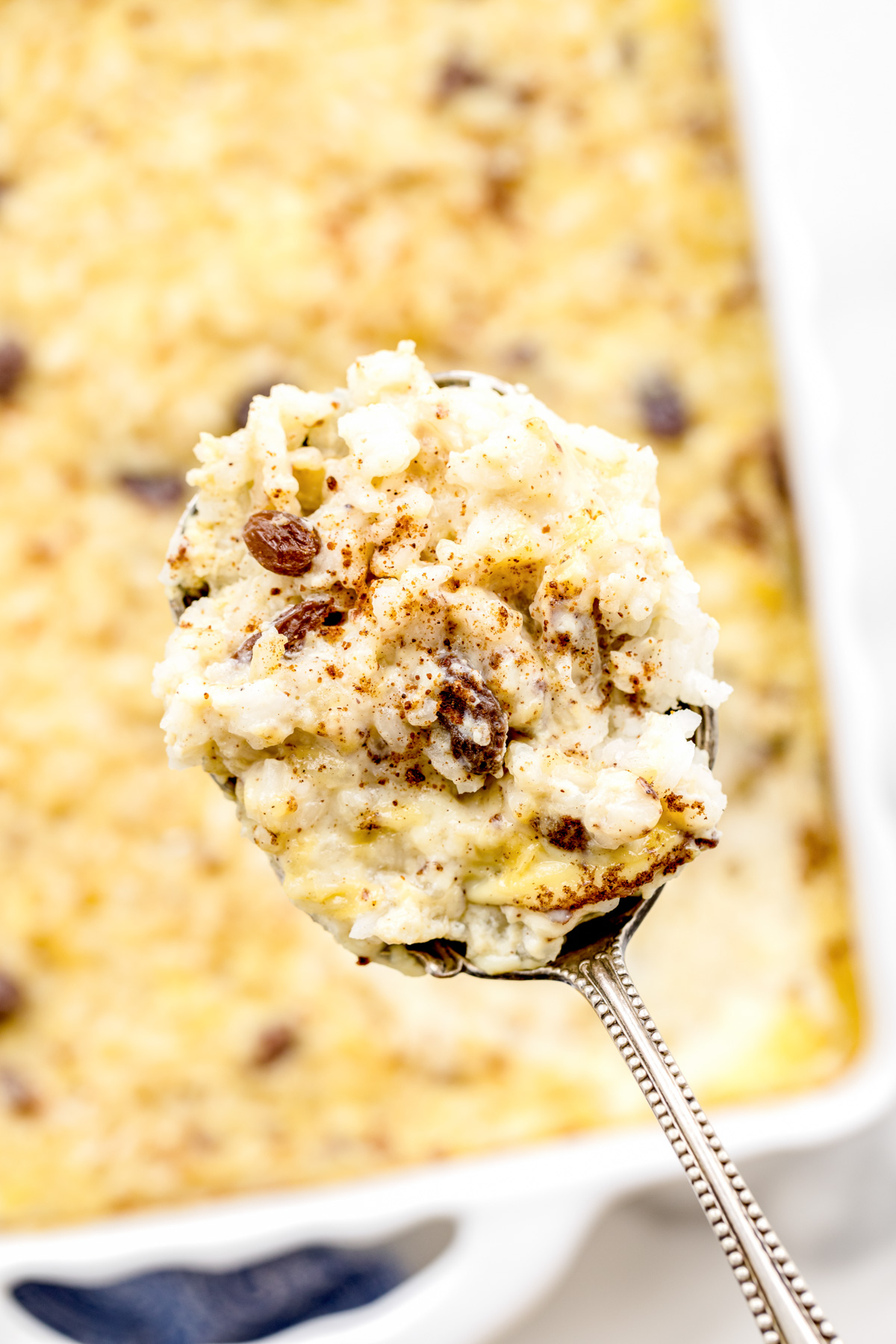 Scooping baked rice pudding from a baking dish.