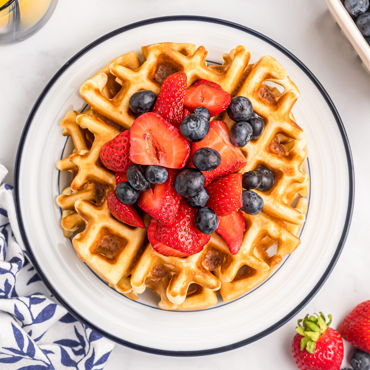 Bisquick waffles with fruit on top on white plate.
