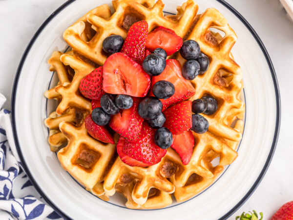Bisquick waffles with fruit on top on white plate.