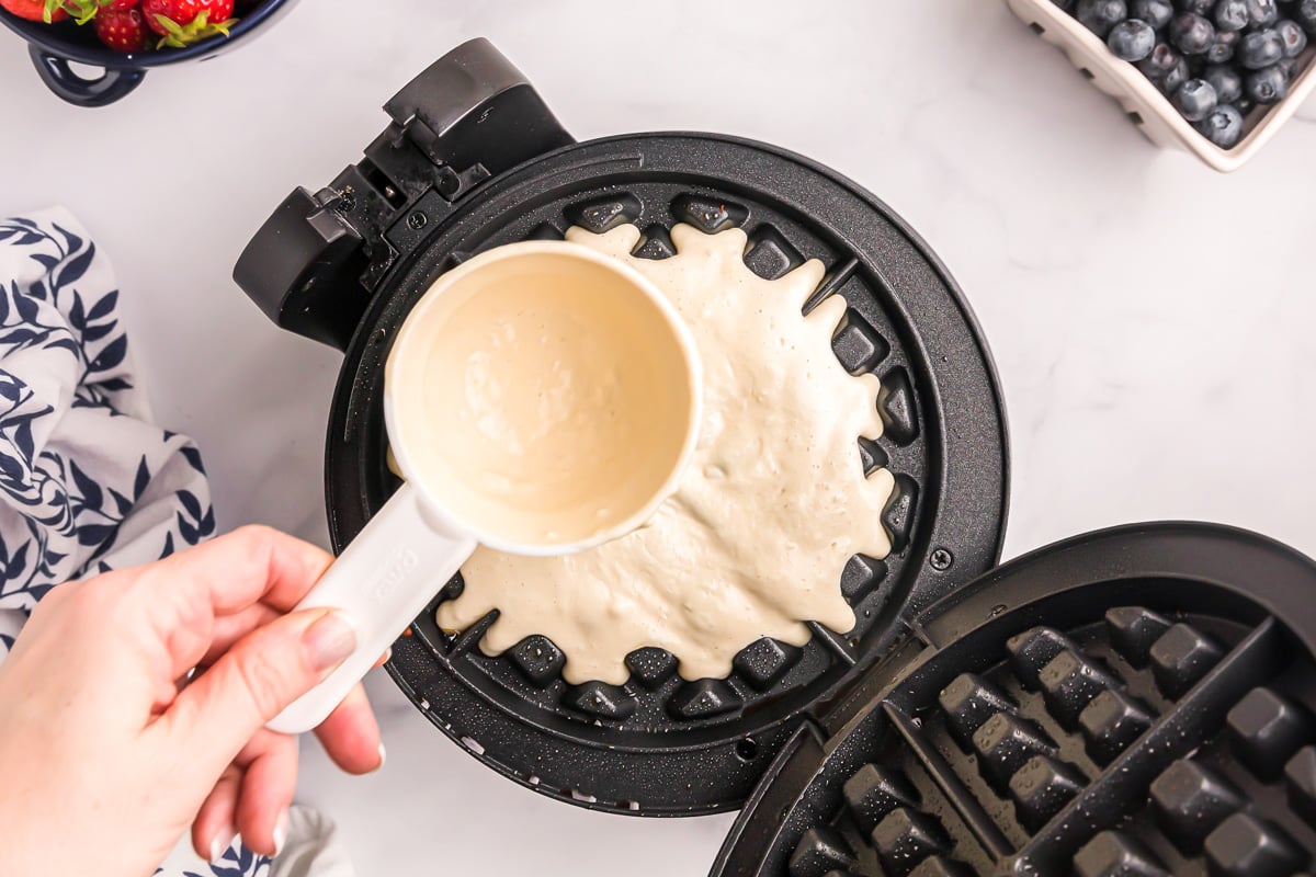 Pouring batter for Bisquick waffle recipe in a waffle iron.