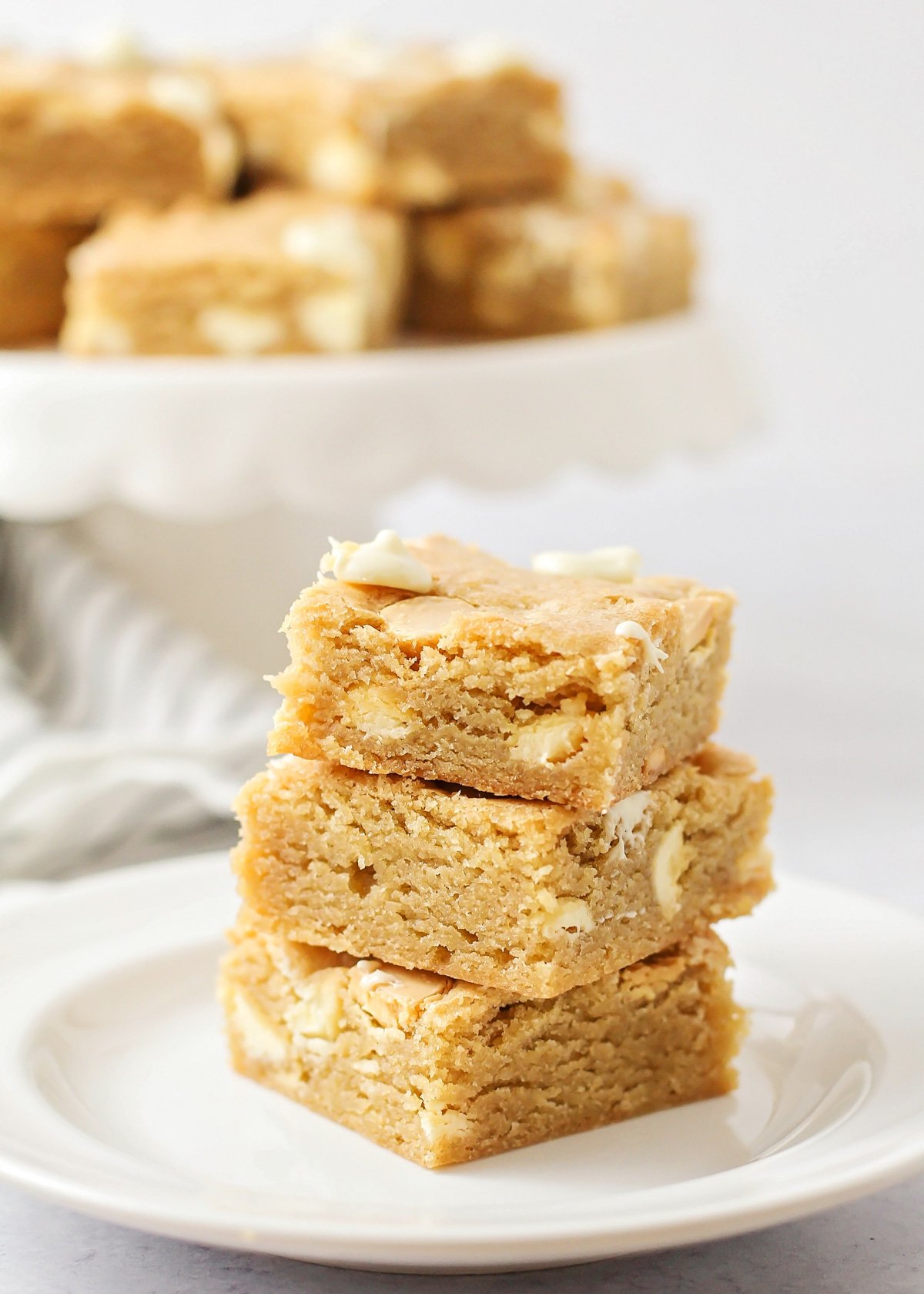 Blondies stacked on a white plate.