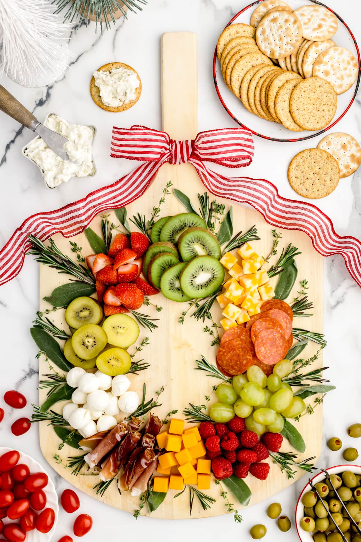 A wreath christmas platter with crackers and fruit.