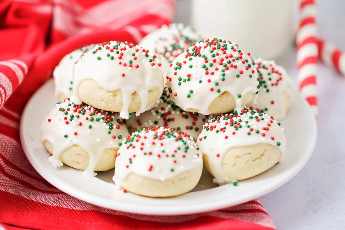 Italian Christmas Cookies with sprinkles on top on white plate.
