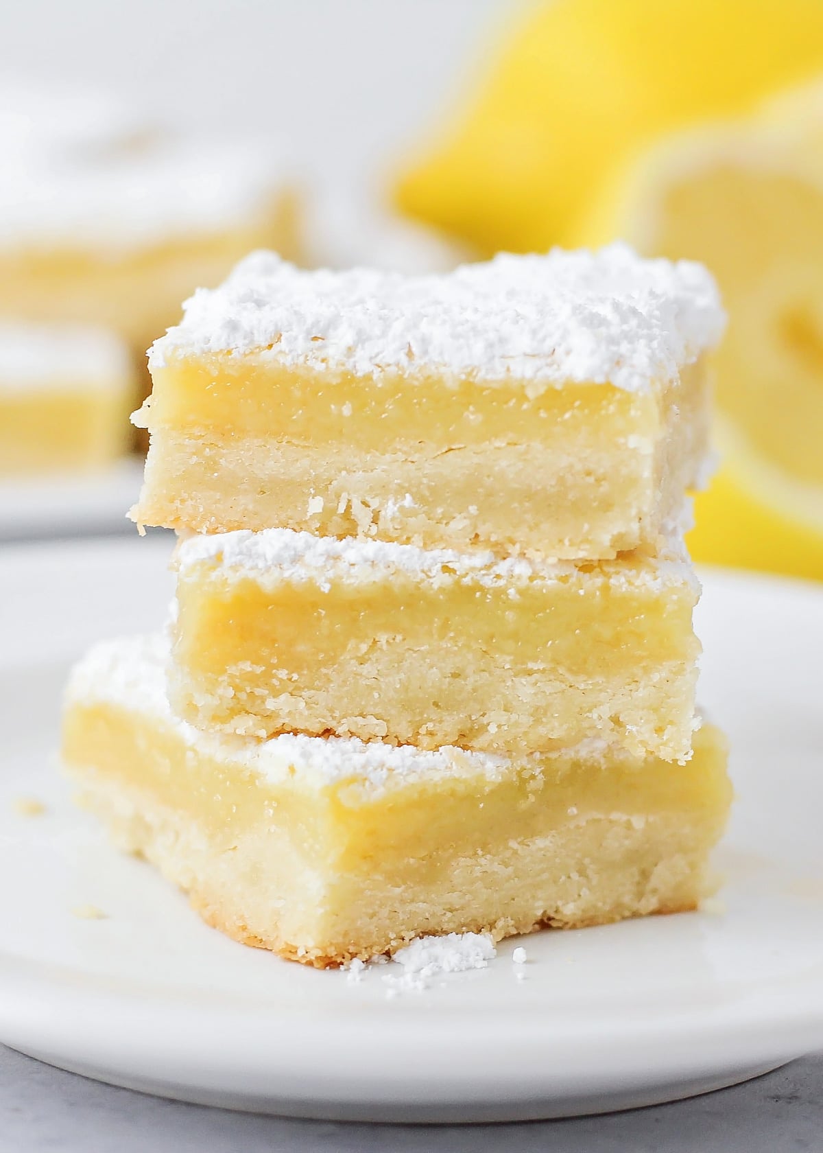 Easy lemon bars stacked on a white plate.