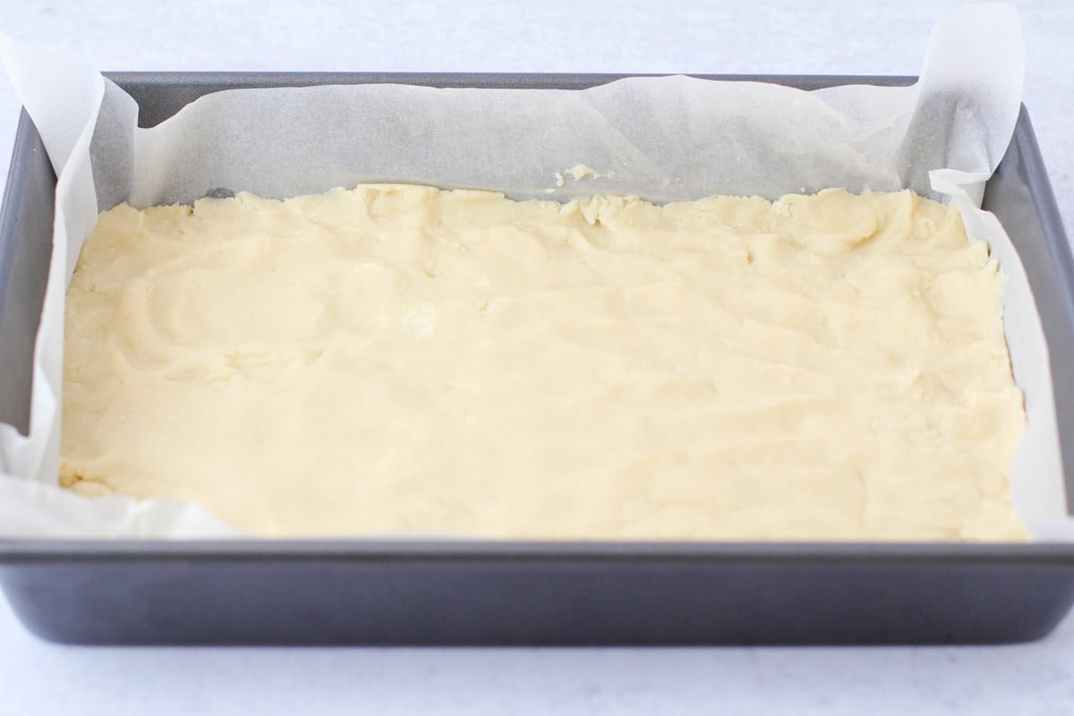 Dough pressed into a pan lined with parchment paper.