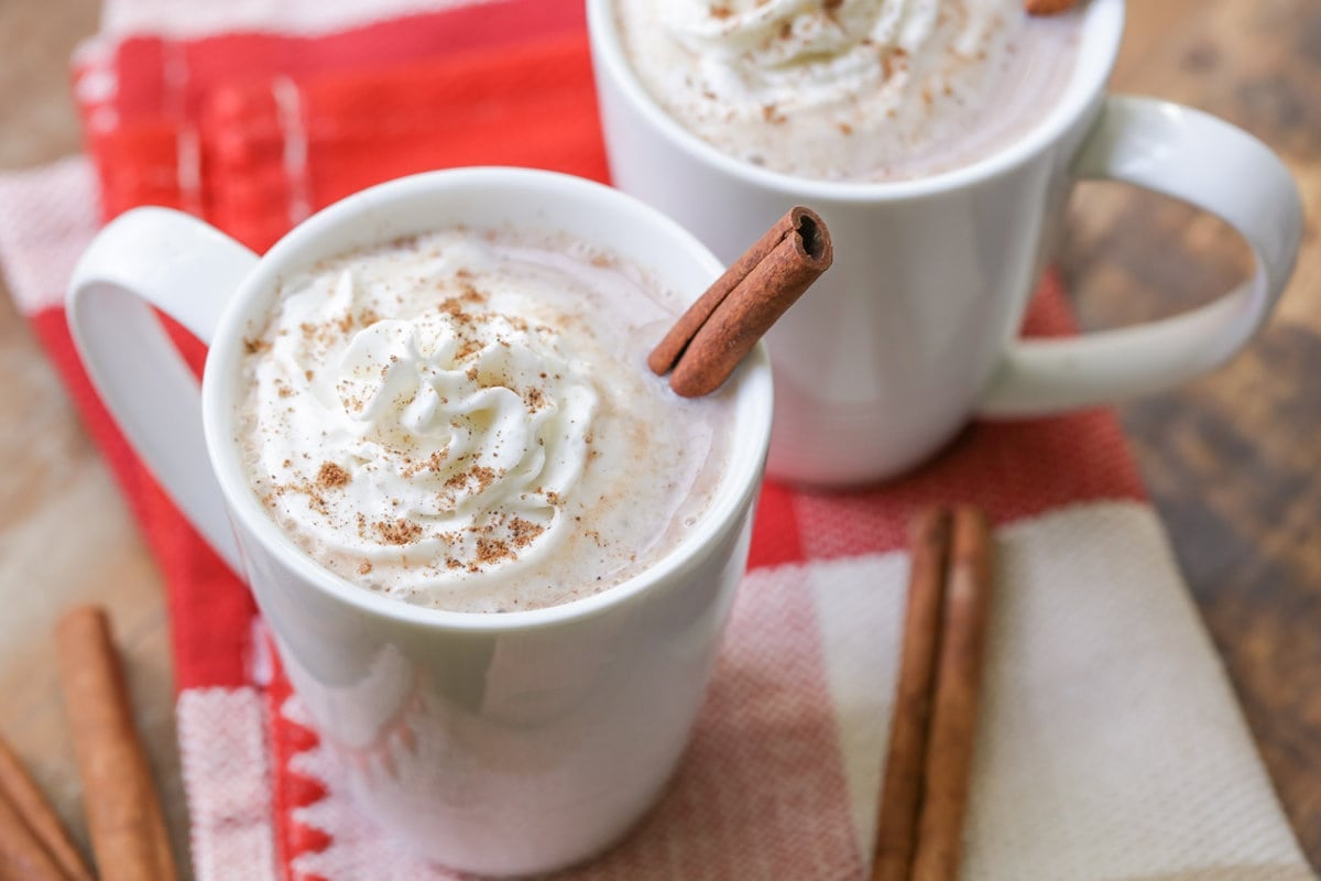 A white mug filled with hot chocolate and a cinnamon stick.