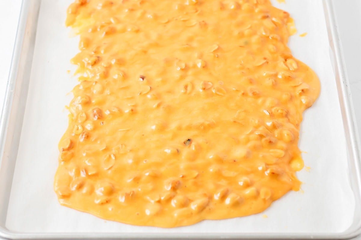 Peanut brittle mixture being spread in pan.